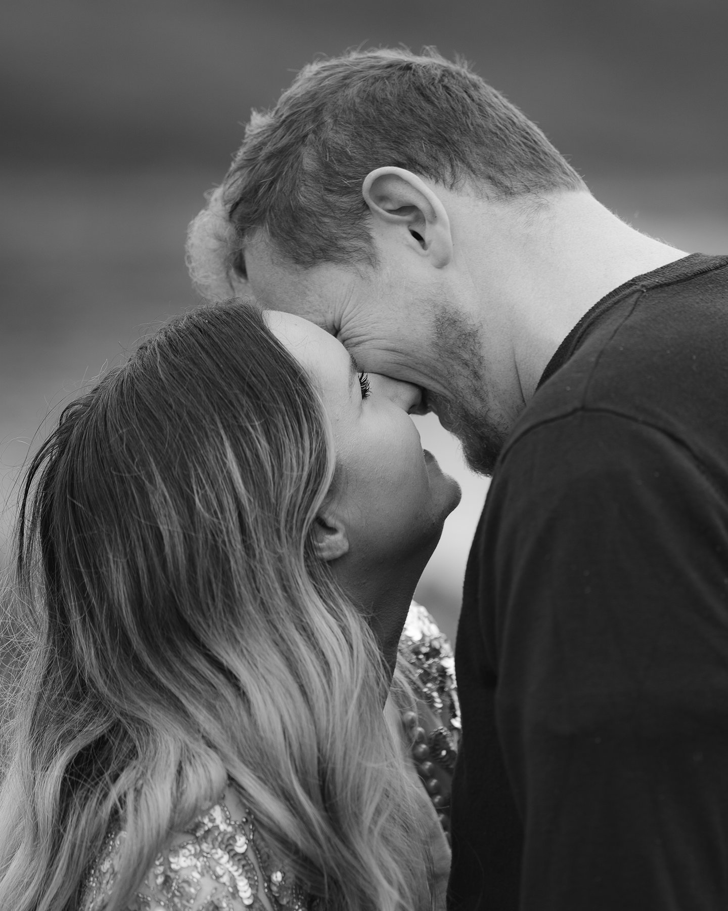 Intimate black and white portrait of engaged couple touching foreheads in tender romantic moment.