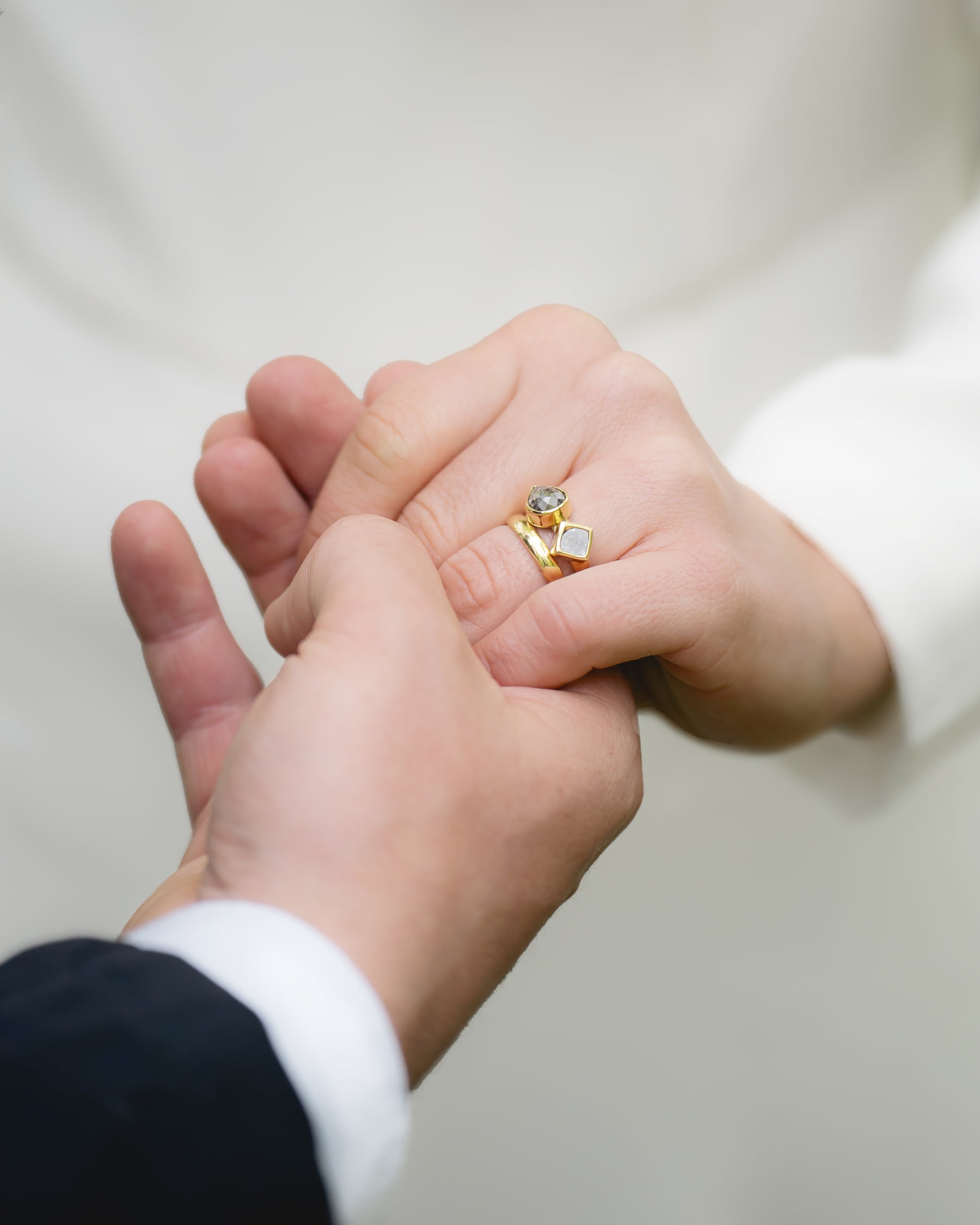 Groom holding bride's hand showing gold wedding ring with gemstones after ceremony.